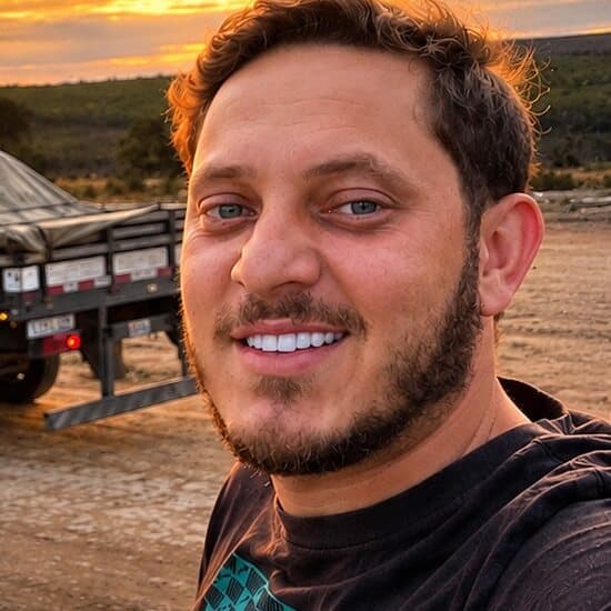 Sampaio sorrindo numa selfie ao lado do caminhão, ao pôr do sol
